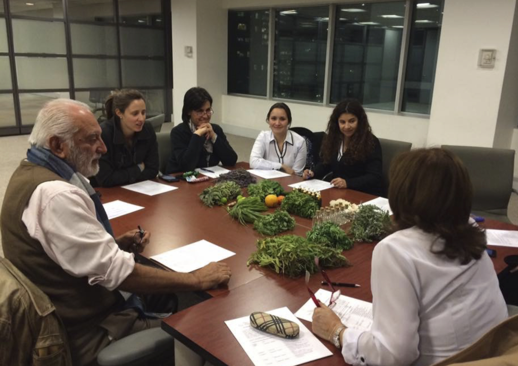 Reunión de trabajo en torno a una mesa con hierbas aromáticas y cítricos.